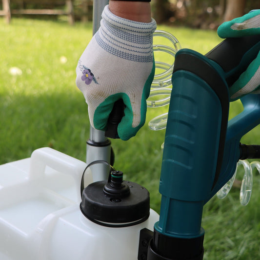 gloved hand removing hose from tank lid of sprayer