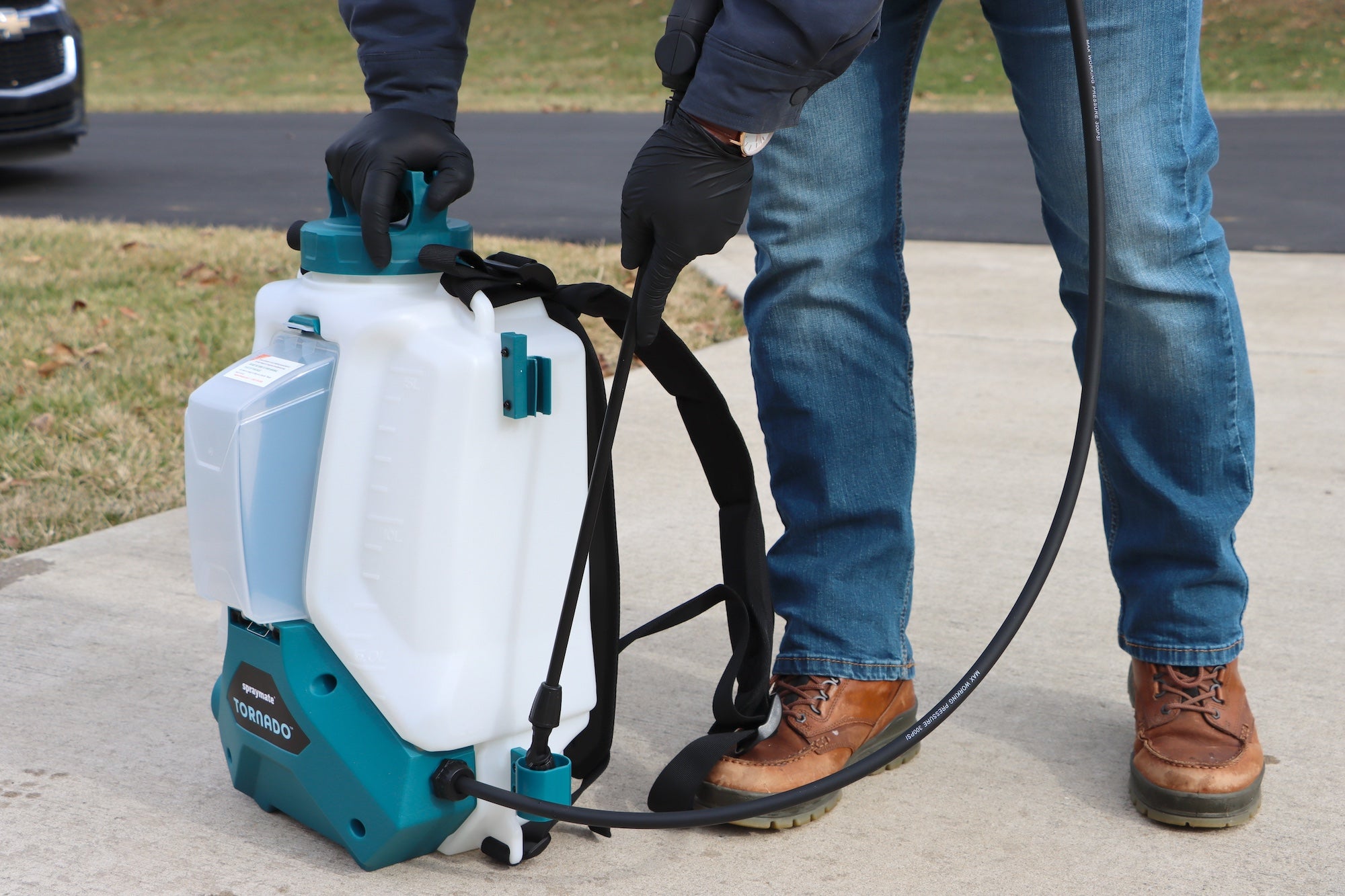 man in jeans putting spray wand into holster on backpack sprayer