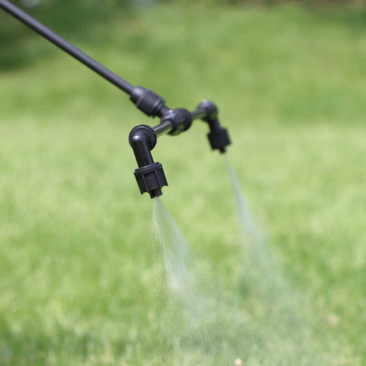 Boom nozzles spraying water on a grassy area