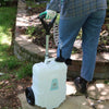 woman standing next to rolling 4 gallon trolley sprayer by garden bed