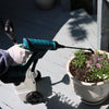 gloved hand spraying flower pot with a battery powered spray gun